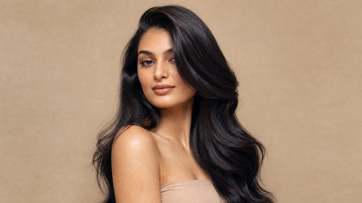Glamorous woman with flawless, full, glossy dark hair and a natural-looking hairline in soft studio light