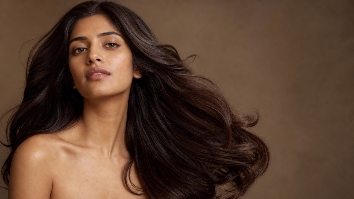 South Asian woman with long, glossy, voluminous dark brown hair in soft editorial studio lighting