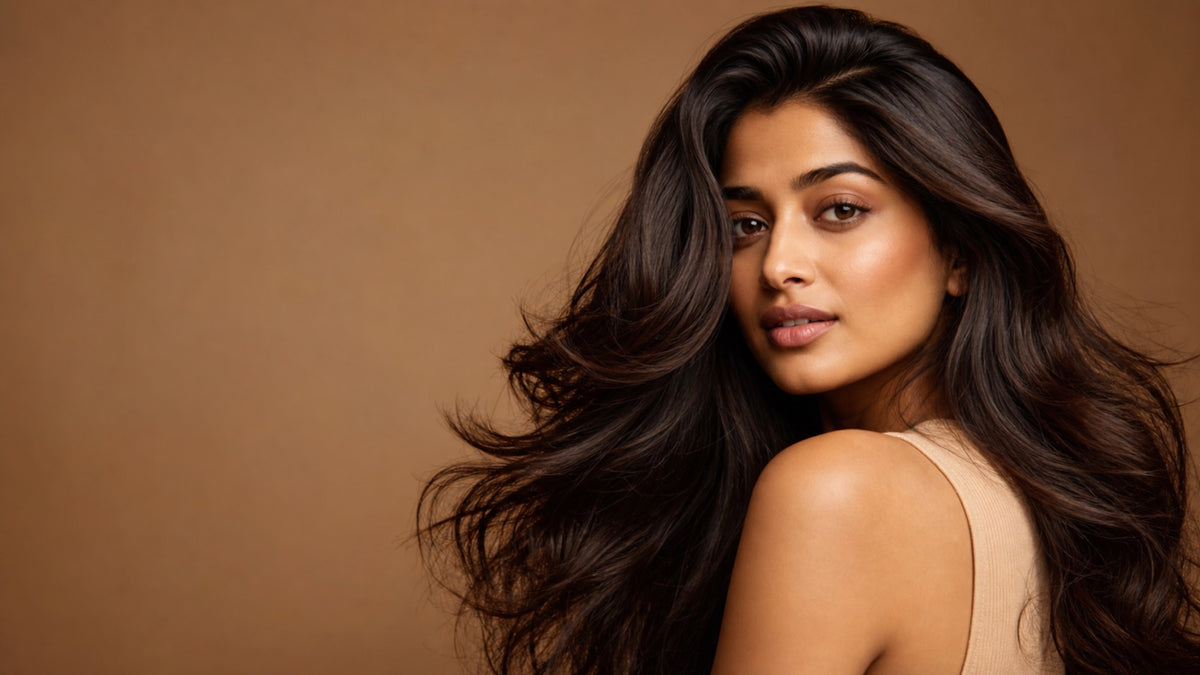 South Asian woman with long, glossy, healthy dark brown hair in soft waves, editorial beauty portrait