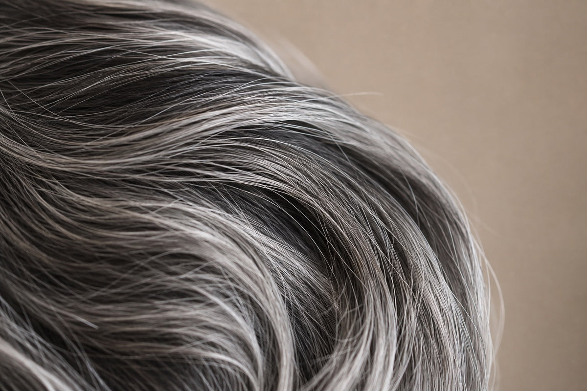 Natural salt-and-pepper human hair — intermingled silver and dark strands, glossy.