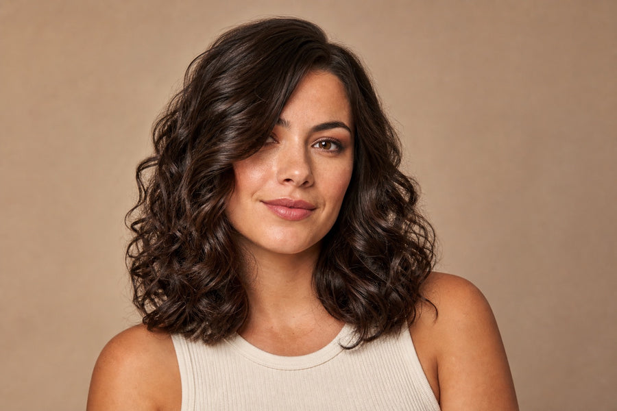 A woman with medium-length hair styled in soft glossy loose curls.