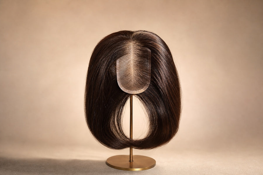 A natural silk-base hair topper with full healthy hair on a clean stand.