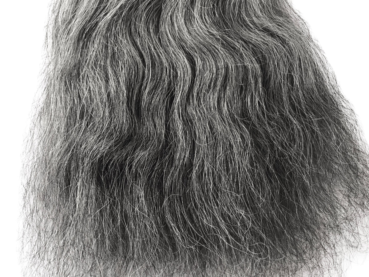 Close-up of salt and pepper grey human hair weft showing mixed grey and dark strands