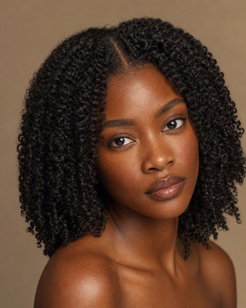 Black woman with natural-black kinky deep-curly hair and a clean natural part, showing the achievable look