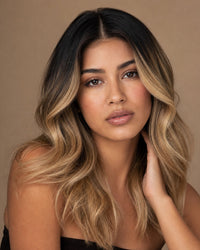 Model showing the achievable ombre look: natural-black roots melting into golden-blonde ends with a flawless middle part