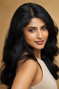Model showing the achievable look: elegant woman with full, healthy natural-black hair and a seamless natural part